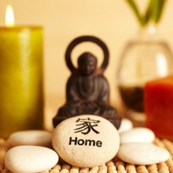 Spa still life buddha statue and river rock, bamboo in vase, and candles, and home river rock in Japanese characters